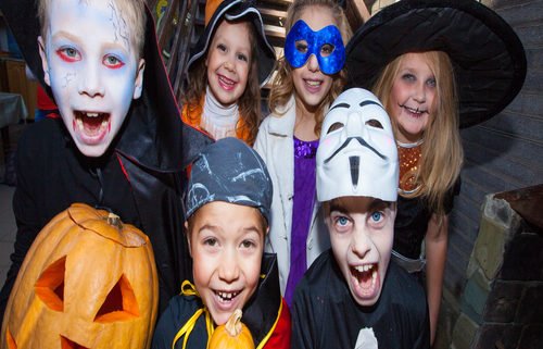 Children in halloween costumes show funny faces