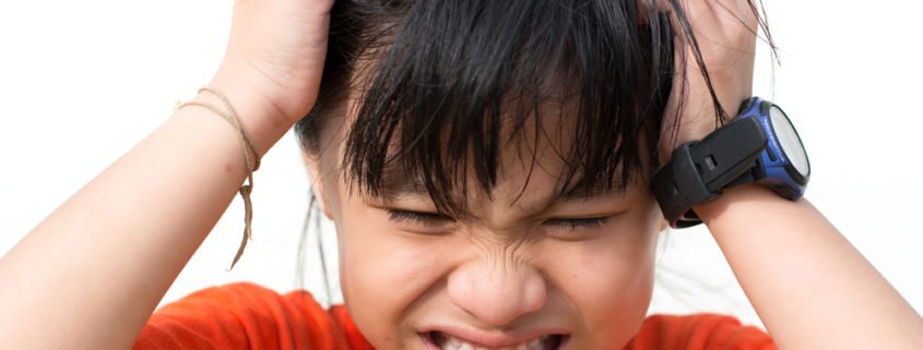 Little kid scratching their head making a irritated face because they have head lice