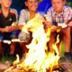 Kids smiling and roasting marshmallows around a campfire at summer camp
